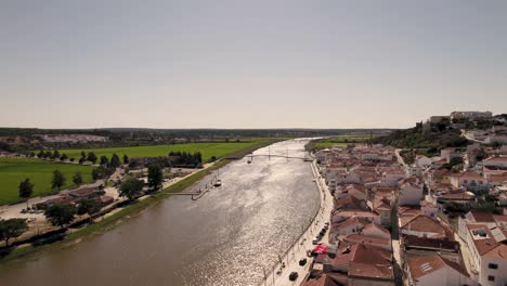 Aerial-dolly-in-overlooking-at-sado-river,-riverside-parish-townscape-and-agriculture-lands