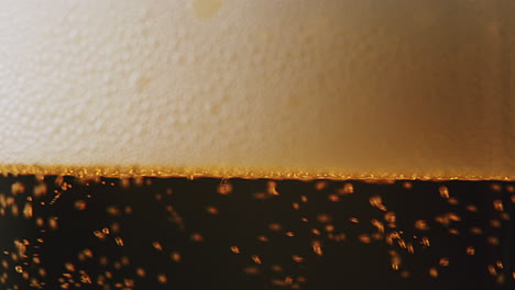 Extreme-close-up-of-beer-foam-filling-up-a-clean-glass