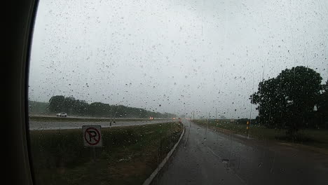 Heavy-rain-hitting-a-large-windshield-of-a-vehicle-that-was-waiting-out-the-rain-storm-at-a-rest-area-along-the-interstate