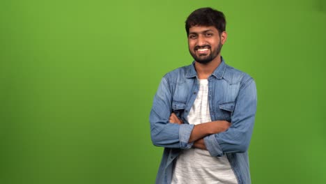 Asian-bearded-man-with-toothy-grin-standing-tall-in-front-of-green-screen-and-greeting
