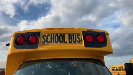 School-bus-close-up-circle-right-showing-red-lights-in-school-parking-lot
