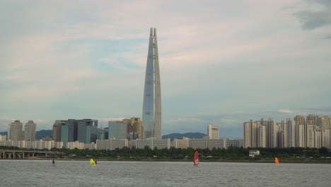 Windsurfing-on-the-Han-River-in-Seoul,-South-Korea-with-the-Lotte-World-Tower-in-the-background