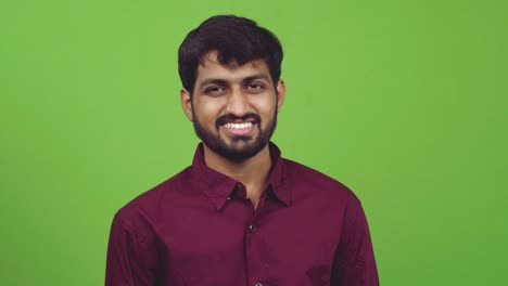 Attractive-Indian-man-looking-towards-camera-and-smiling,-isolated-on-green-screen