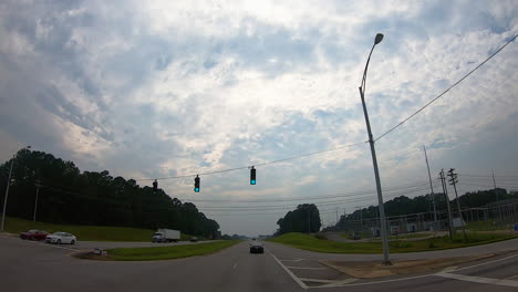 POV---driving-through-a-green-light-at-an-intersection-of-two-busy-roads-in-rural-Alabama-on-a-cloudy-summer-afternoon