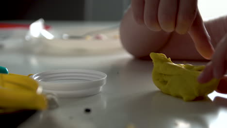 Hands-Of-A-Child-Sculpts-From-Dough-Over-White-Table