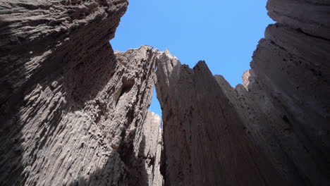 Natural-Wonders-of-Cathedral-Gorge-State-Park,-Low-Angle-View-of-Bentonite-Clay-Cliffs-in-Narrow-Slot-Canyon-Under-Blue-Sky,-Nevada-USA