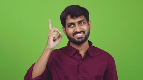 Attractive-man-showing-thinking-gesture-while-pointing-to-his-forehead,-isolated-on-green-screen