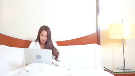 Hübsche-Asiatische-Frau-Mit-Laptop-Im-Bett,-Die-Den-Siegeserfolg-Feiert,-Vollbild-Zeitlupe