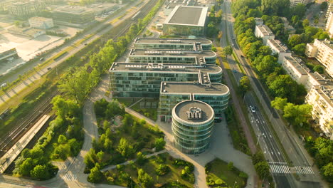 Aerial-view-of-modern-building-surrounded-by-green-trees-and-cars-on-road-in-Gdynia