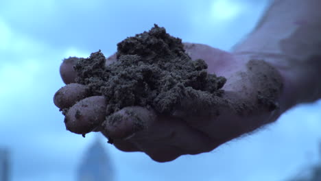 Worker's-Hand-With-Heap-Of-Soil,-Dropping-In-Slow-Motion