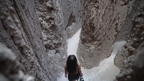 Young-Woman-With-Photo-Camera-Walking-in-Surreal-Slot-Canyon-in-Cathedral-Gorge-State-Park,-Nevada-USA