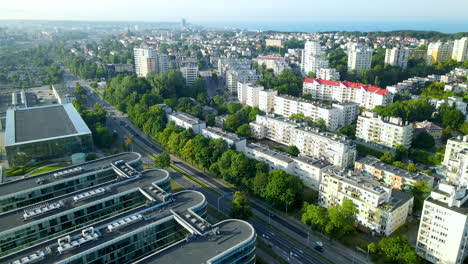 Aerial-View-Of-PPNT-Building-With-City-And-Apartment-Buildings-Along-The-Highway-In-Gdynia,-Poland