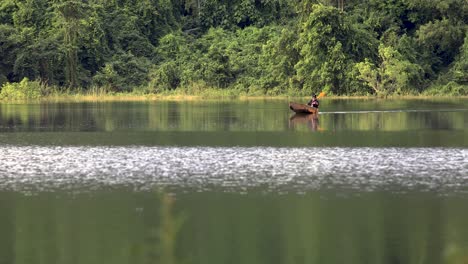 Un-Hombre-Navega-En-Canoa-En-Un-Lago-Reflectante-Con-Un-Fondo-Forestal-En-Tailandia