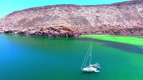 Rising-Drone-View-of-Anchored-Sailboat-in-Emerald-Bay-near-Desert-Island-Coast