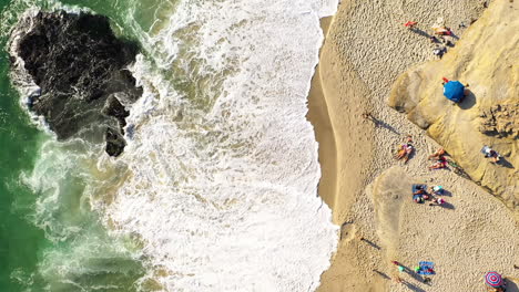 Top-down-View-Of-People-Sunbathing-And-Relaxing-At-Windansea-Beach-With-Foamy-Waves-In-California,-USA