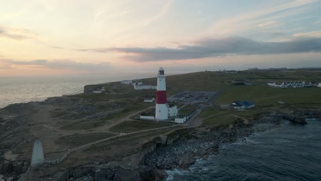 Drone-moves-around-the-Portland-Bill's-lighthouse-on-a-beautiful-summer-sunset,-in-Dorset,-England
