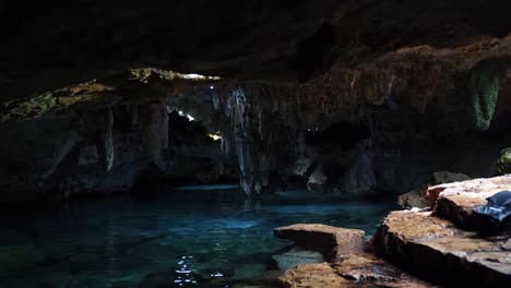 Tilt-up-shot-of-a-beautiful-underground-Mexican-Cenote-with-Stalactites-growing-from-the-roof-and-crystal-clear-blue-fresh-water-in-a-eco-park-Kantun-Chi-on-Playa-del-Carmen-in-Riviera-Maya,-Mexico
