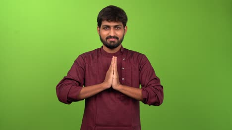 Young-attractive-man-showing-namaste-gesture,-isolated-on-green-screen