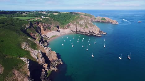 4K-aerial-static-drone-footage-of-many-sailboats-moored-on-a-fantastic-beach-on-the-Isle-of-Sark,-UK
