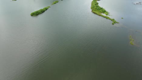Aerial-footage-from-land-to-water-revealing-a-truck-small-islands,-water-reflecting-the-sky,-Muak-Klek,-Saraburi,-Thailand