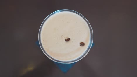 Hand-placing-three-coffee-beans-on-to-foam-of-espresso-martini,-top-down