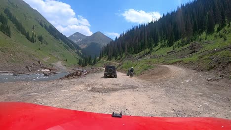 POV-over-red-vehicle-hood-on-narrow-off-road-trail-trail-while-driving-past-dirt-bikes-and-OHV