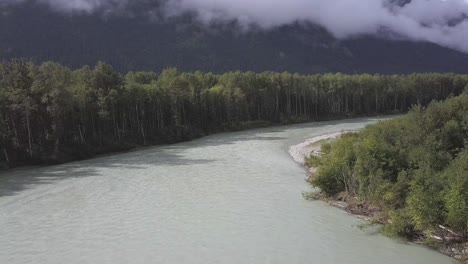 Aerial:-Bella-Coola-River-curves-amid-tall-green-trees-and-mountains