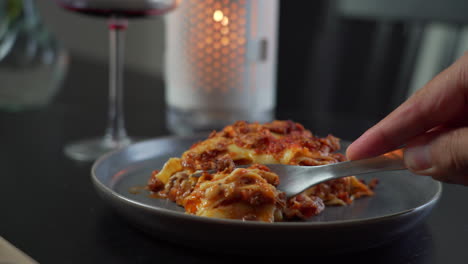 Man-cutting-a-beautiful-piece-of-a-sumptuous-traditional-Italian-lasagna-at-a-romantic-restaurant