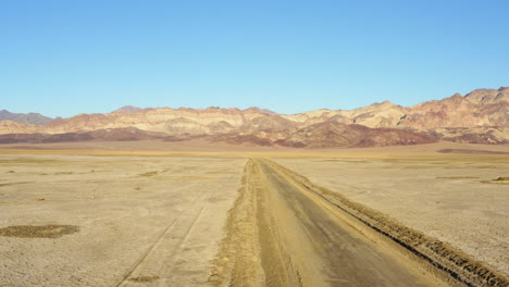 Birds-eye-view-of-SUV-jeep-on-road-amidst-hot-dry-barren-terrain-of-Death-valley-national-park
