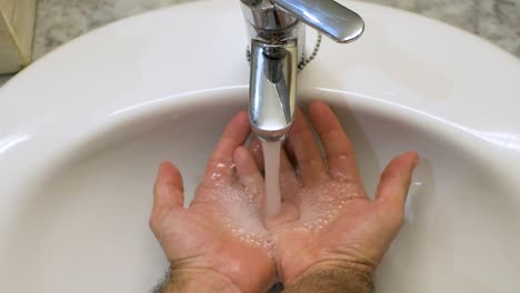 Open-tap-in-the-sink-with-water-falling-into-hands