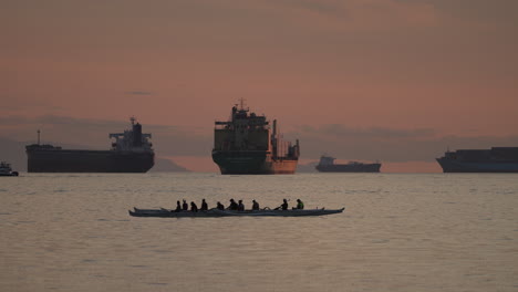 Silhouetted-Group-Of-People-Riding-On-A-Paddle-Boat-On-Water-Surface-In-Vancouver,-Canada-At-Sunset