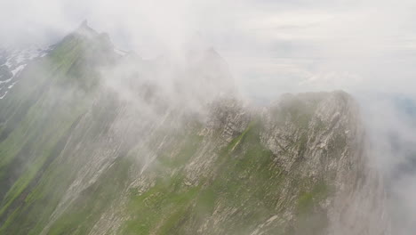 Rotating-drone-shot-of-Altenalp-Turm,-with-clouds-covering-the-mountainside
