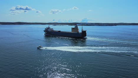 Speedboat-And-Cargo-Ship-Sailing-In-The-Ocean-Near-Lysekil-In-Bohuslan,-Sweden