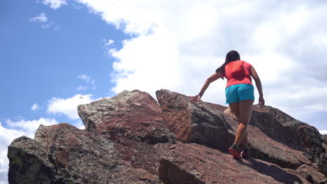 Young-Woman-Climbing-on-Top-of-The-Rock-Above-Clouds-and-Sky-on-Sunny-Summer-Day-Slow-Motion-Full-Frame