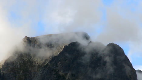Morning-cloud-fog-dissipates-around-rocky-mountain-peak-at-dawn