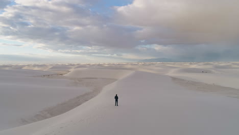4K-aerial-passing-over-person-revealing-beautiful-white-sand-dune-field-sunrise