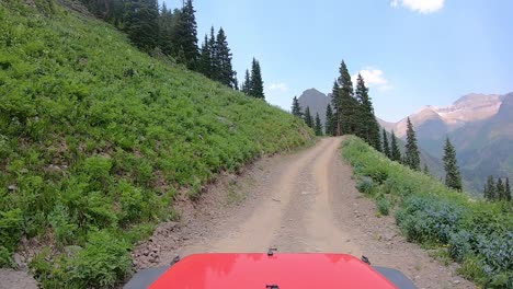 POV-over-vehicle-hood-on-narrow-off-road-trail-trail-cut-into-mountain-side