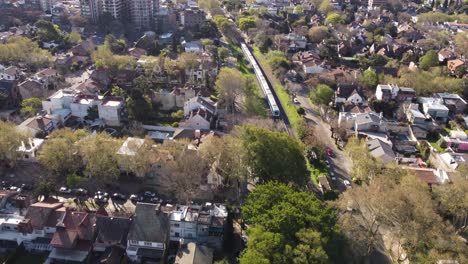 Aerial-view-of-a-train-going-far-Vicente-López-residential-area-Buenos-Aires,-Argentina
