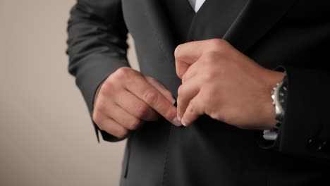 Close-up-shot-of-a-groom-getting-ready-and-buttoning-his-black-wedding-suit-wearing-wooden-bow-tie-and-elegant-watches