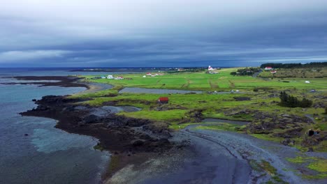 Luftaufnahme-Der-Zerklüfteten-Küste-Mit-Grünen-Feldern-In-Der-Nähe-Von-Gardakirkjugardur-In-Gardabaer,-Island