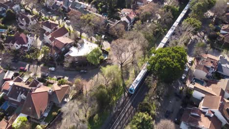 Aerial-top-down-of-train-driving-on-rails-in-suburb-district-of-Buenos-Aires,Argentina