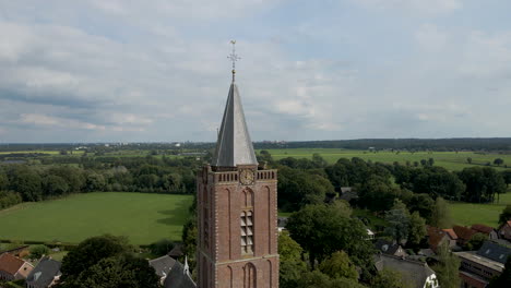 Jib-up-of-tall-church-tower-in-a-small-rural-town-overlooking-green-meadows