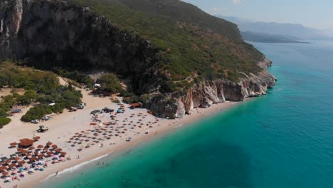 Stunning-reveal-shot-of-beautiful-Gjipe-Beach-in-Albania-with-sun-umbrellas
