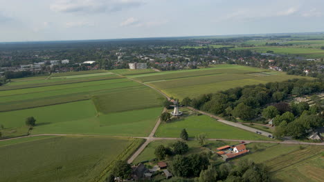 Aerial-of-spinning-windmill-in-beautiful-green-rural-town---drone-flying-backwards