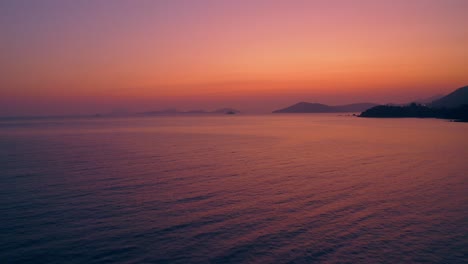 Wunderschöne-Drohnenaufnahme-Einer-Natürlichen-Küste-Während-Des-Sonnenuntergangs,-Das-Licht-Ist-Klar,-Rot,-Lila-Und-Golden-Und-Das-Meer-Reflektiert-Diese-Farben