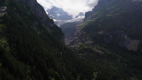 Drone-shot-of-mountains-near-Grindelwald,-in-Switzerland’s-Bernese-Alps,-with-a-waterfall-in-the-distance