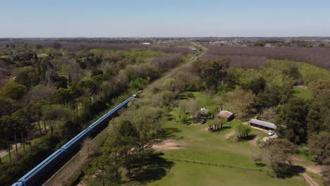 Aerial-view-of-a-blue-train-in-rural-area-of-Buenos-Aires,-Argentina