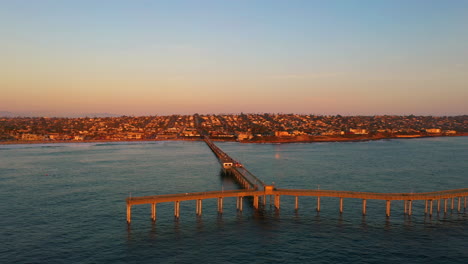 Drone-orbit-around-Ocean-Beach-Pier-in-San-Diego,-California-during-warm-sunset-colors