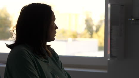 Woman-in-hospital-room-looking-out-of-window