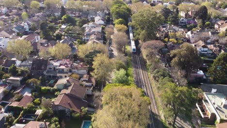 Train-leaving-town-Vicente-Lopez-residential-area,-Buenos-Aires